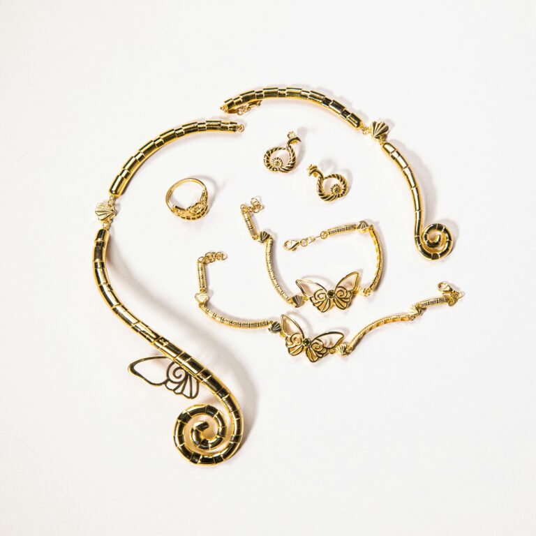 A stylish arrangement of gold jewelry with butterflies and spirals on a white background.